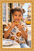 Child wearing the printed T-shirt and eating a pastel de nata in Lisbon inside the gold frame